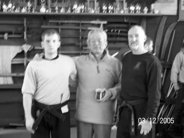 Three martial artists together in a dojo after training in 2005.